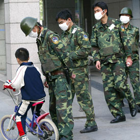 Un grupo de guardias protegidos con mascarillas, en una calle de Shanghai.