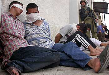 Un soldado israelí vigila a unos palestinos detenidos ayer en Qalqilya.