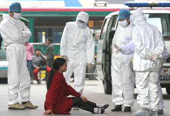 Una mujer sospechosa de tener la neumonía es interrogada por un equipo de enfermeros en la estación de Pekín.