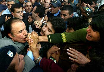 El ex candidato Carlos Menem era aclamado ayer por sus seguidores mientras les anunciaba su renuncia a la segunda vuelta de las elecciones.