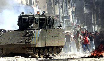 Jóvenes palestinos lanzan piedras contra un tanque israelí en un campo de refugiados de Cisjordania.