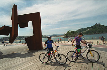 El 'bidegorri', o camino rojo para los ciclistas en San Sebastián, junto a la escultura de Oteiza 'Construcción vacía'.