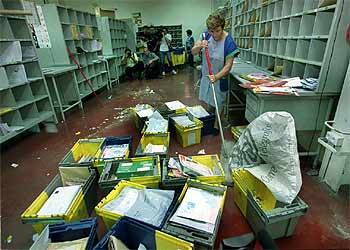 Una mujer de la limpieza retira los destrozos causados por la explosión en la oficina de Correos. rnrn CARLES FRANCESC