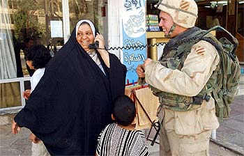 Una mujer iraquí escucha la radio de comunicaciones de un soldado estadounidense de patrulla por Bagdad.