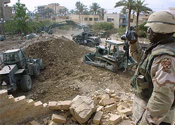 Un soldado de EE UU toma fotografías de las ruinas de una casa en la que podrían hallarse los restos de Sadam.