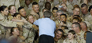 George W. Bush, rodeado de soldados, durante su visita de ayer al cuartel general estadounidense en Qatar.
