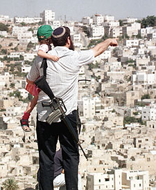 Un colono israelí, con su hijo, observa un asentamiento en Hebrón.
