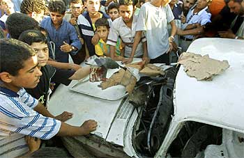 Varios niños palestinos se agrupan alrededor del automóvil atacado ayer por un helicóptero israelí en Gaza.
