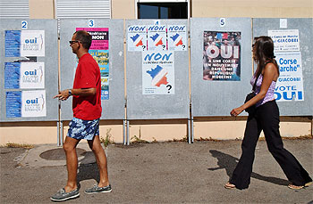 Dos votantes pasan junto a carteles que piden el voto para el  sí  y el  no  en Ajaccio.