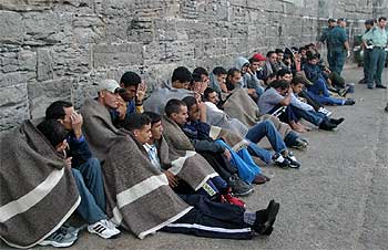 Parte del grupo de 73 inmigrantes interceptados ayer en el Estrecho se protege con mantas tras su llegada al puerto de Tarifa (Cádiz).
