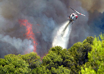 Un helicóptero lanza agua sobre las llamas en los bosques de Sant Llorenç Savall, en Barcelona.
