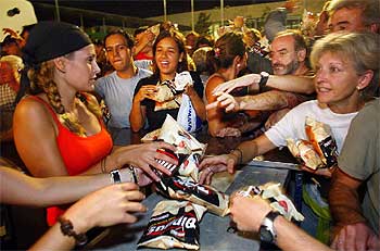 Los asistentes al partido recogen bolsas de comida.