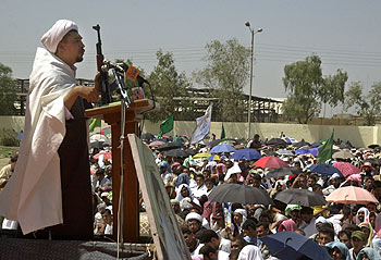 Un imam iraquí sostiene un fusil AK-47 durante la oración de los viernes ante cientos de personas, ayer, en un barrio de Bagdad.