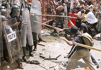 Varios manifestantes atacan con palos a la policía mexicana en una protesta contra la OMC en Cancún.