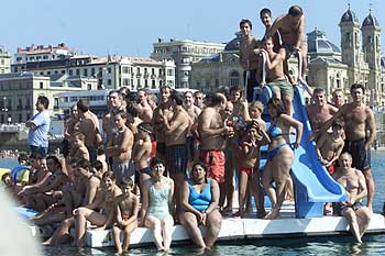 Muchos bañistas aprevecharon el buen tiempo para seguir el desarrollo de la regata desde un gabarrón de la Concha.