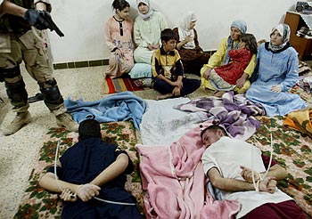 Un soldado norteamericano apunta a sospechosos de colaborar con la guerrilla iraquí en presencia de sus familiares, ayer, en Tikrit.