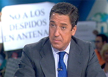Eduardo Zaplana, ayer, en el programa  La Respuesta  mientras los trabajadores de Antena 3 muestran sus pancartas de protesta.
