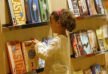 Una niña hojea libros en las instalaciones de Ifema, en Madrid, donde se celebra Liber 2003.