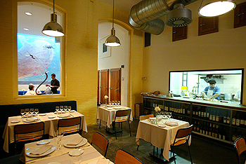 Un ventanal de cristal separa la cocina del comedor de L'Arrel del Born, en el barrio barcelonés del Born.