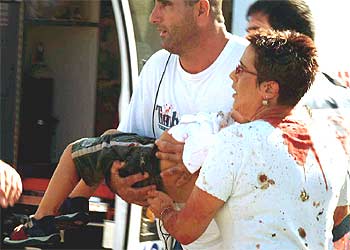 Dos transeúntes alejan a un niño herido del lugar del atentado en Haifa, al norte de Israel.