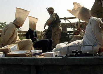 Soldados de EE UU custodian a tres iraquíes detenidos ayer en Tikrit, ciudad natal de Sadam Husein.