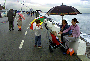 Una familia en el rompeolas del puerto de Barcelona, ayer.