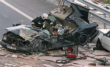 Un bombero observa el cadáver del conductor del Mercedes 300 fallecido tras caerle encima los tablones de aglomerado en la N-I.