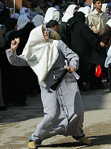 Una mujer lanza piedras contra la sede de la Autoridad Monetaria Palestina.