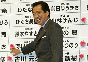 Naoto Kan sonríe mientras señala el nombre de un candidato de su partido que resultó elegido el domingo.