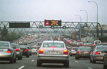 Una larga hilera de automóviles circula con lentitud por la A-6, a la altura de la cuesta de las Perdices. Sobre sus cabezas, un cartel indica que hay tráfico lento a lo largo de tres kilómetros más.
