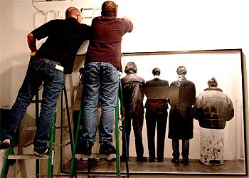 Varios trabajadores colocan la obra  Facing the wall , en la feria Art Basel Miami Beach, en Florida