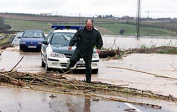 Un agente sortea una carretera inundada ayer en el término municipal de Palomares del Río.