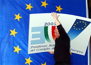 Un trabajador lleva un cartel con el logotipo de la presidencia italiana, ayer en Bruselas.