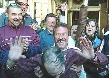 Algunos clientes del bar Asturias, en Valencia, celebran que el propietario del establecimiento, que aparece inclinado, repartió parte del    'gordo'. 