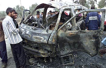 Un grupo de iraquíes, ante los restos de un vehículo destrozado por un atentado, ayer en Bagdad.
