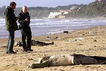 Dos guardias civiles, en una playa de Rota junto al cuerpo de uno de los inmigrantes fallecidos.