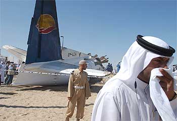 Un agente de seguridad de los Emiratos Árabes se cubre la boca y la nariz al pasar cerca del avión siniestrado ayer.