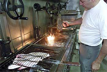 Víctor Arguinzoniz, en la parrilla del restaurante Etxebarri, en Atxondo (Vizcaya). Abajo, el caserío donde se sitúa.