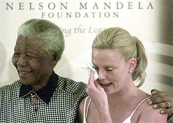 La actriz surafricana Charlize Theron se seca las lágrimas, ayer en Johanesburgo, durante la emocionada visita que hizo al ex presidente Nelson Mandela, quien la toma cariñosamente del hombro.