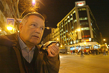 Un simpatizante del PP escuchaba anoche en la calle de Génova los resultados de las elecciones por la radio.
