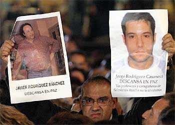 Un manifestante muestra la fotografía de dos alcalaínos fallecidos en el atentado.