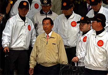 El presidente Chen Shui Bian sale, rodeado de guardaespaldas, del colegio electoral en el que votó ayer.