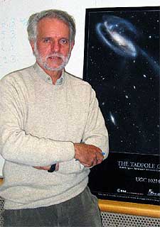 Rudolf Albrech en la sede del ESO, junto a la foto de una galaxia hecha con el  Hubble. 