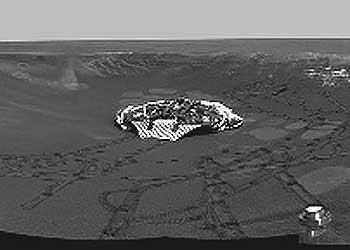 Panorámica del cráter con afloramientos rocosos en el que cayó  Opportunity,  tomada por el robot el lunes pasado desde el borde. Se observan las rodadas y la plataforma en la que llegó.