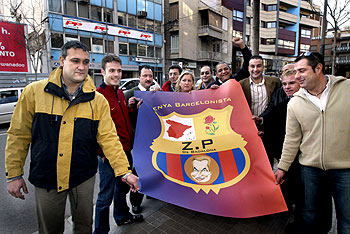 Algunos miembros de la peña ZP muestran su estandarte con la sede del PP al fondo.