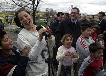 Un grupo de niños y jóvenes de Las Barranquillas  se apodera  del micrófono que antes había utilizado para su discurso Ruiz-Gallardón (detrás).