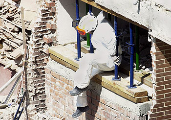 Un miembro de la policía científica sale del edificio destruido.