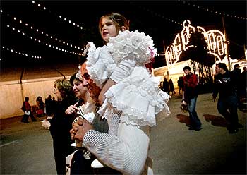 Una familia con la niña a cuestas vestida de faralaes, ayer, en la inauguración de la Feria de Abril.