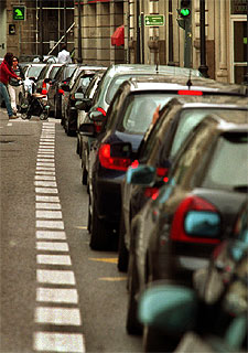 Colas de vehículos en la calle de las Barcas de Valencia para entrar en un aparcamiento.
