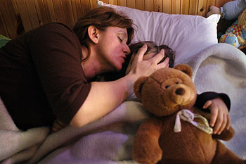 Virginia, enferma de anemia de Fanconi, descansa en la cama junto a su madre.